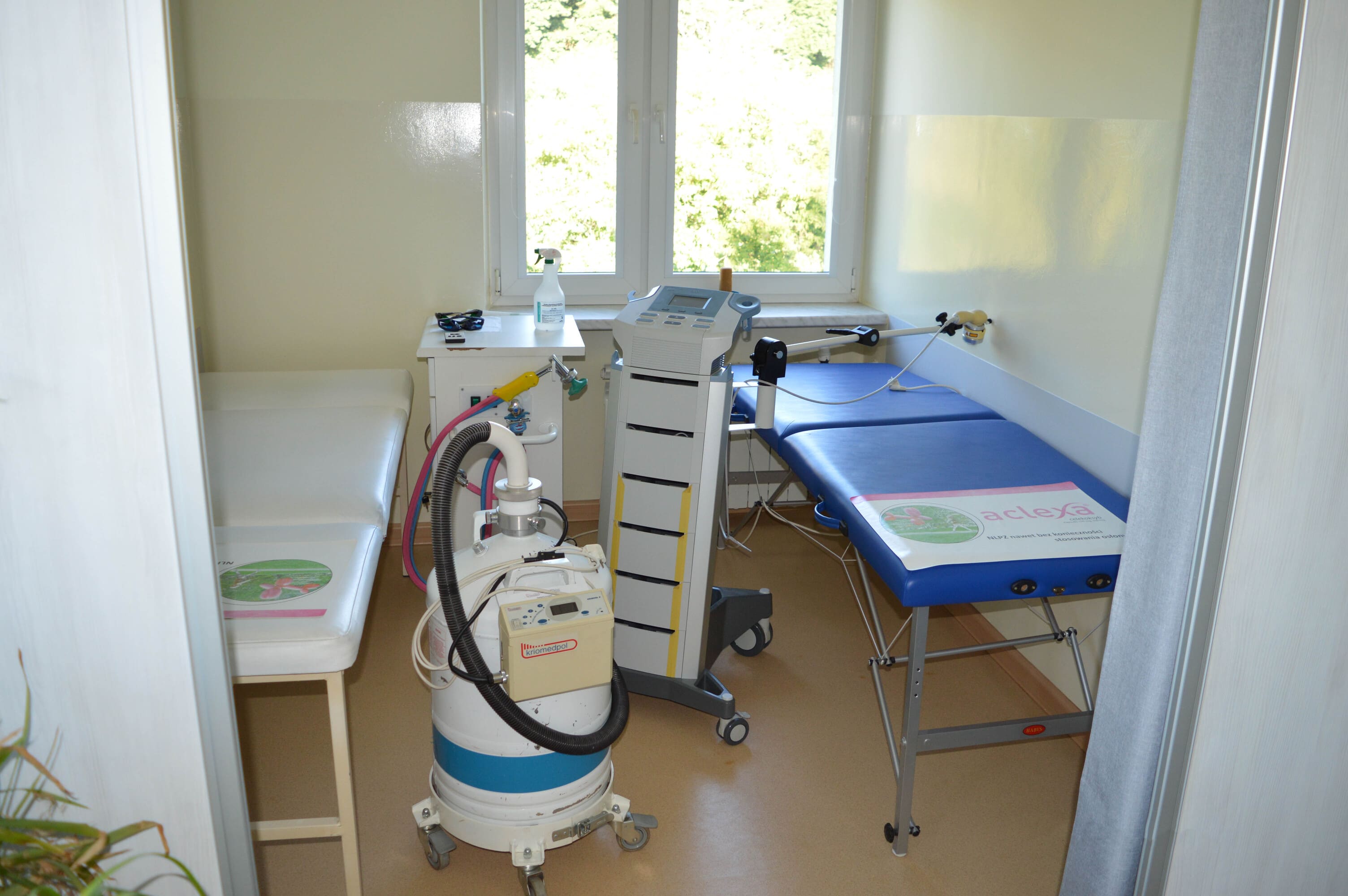 Stanowisko laseroterapii i krioterapii po prawej i lewej stronie widoczne leżanki między którymi ustawione są przyrządy z elektrodami.
